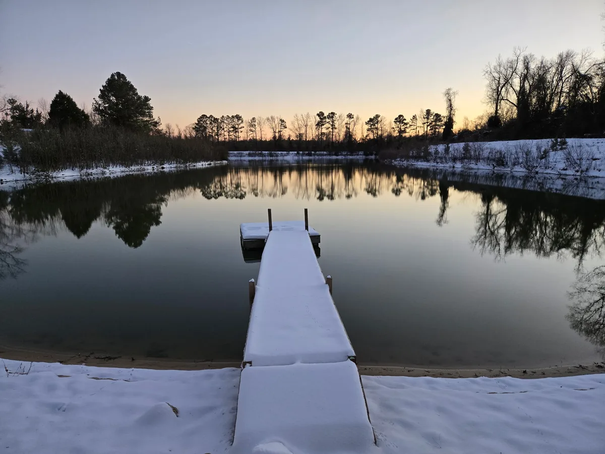 Snow-covered dock on the lake at sunset